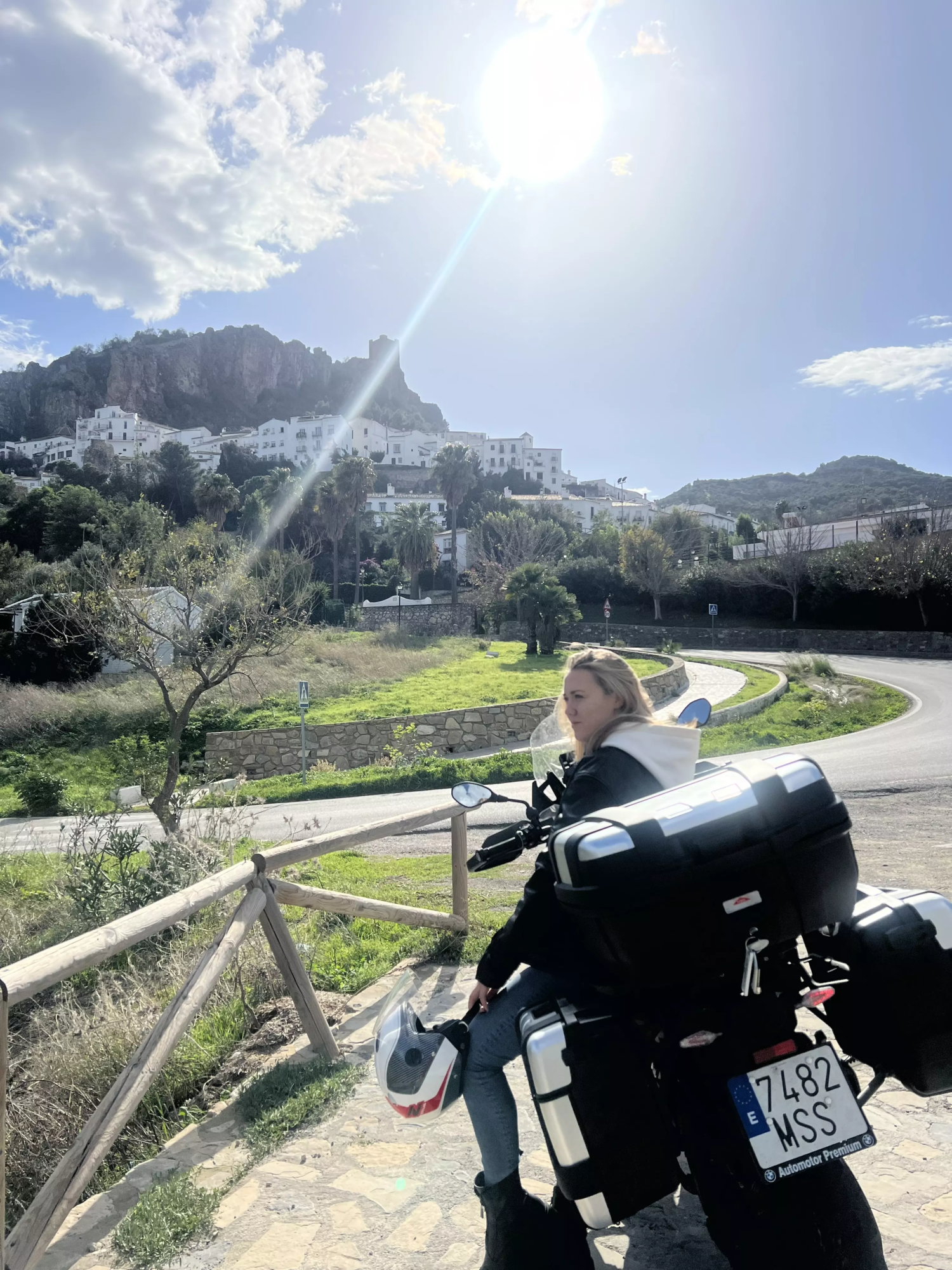 Karlina sur une moto devant un paysage de village
